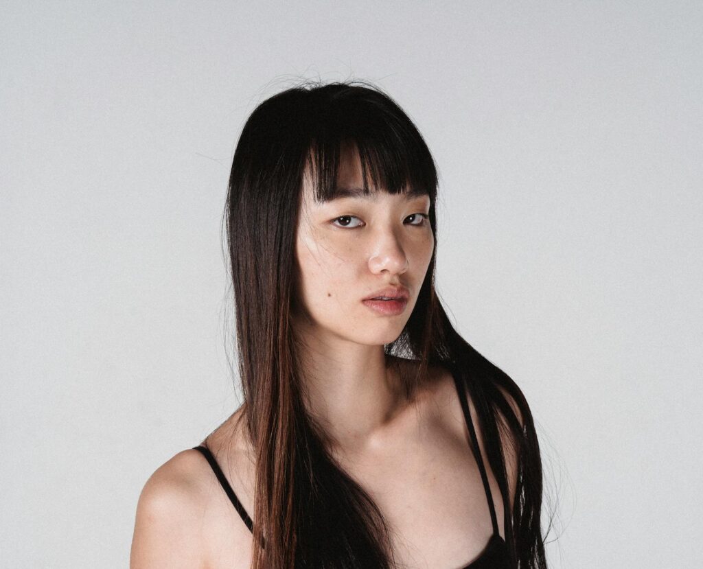 attractive asian woman with long hair against white wall